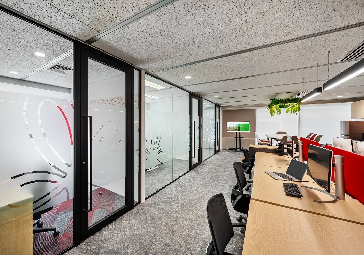 Intersnack open-plan office with red acoustic screens and glass meeting rooms