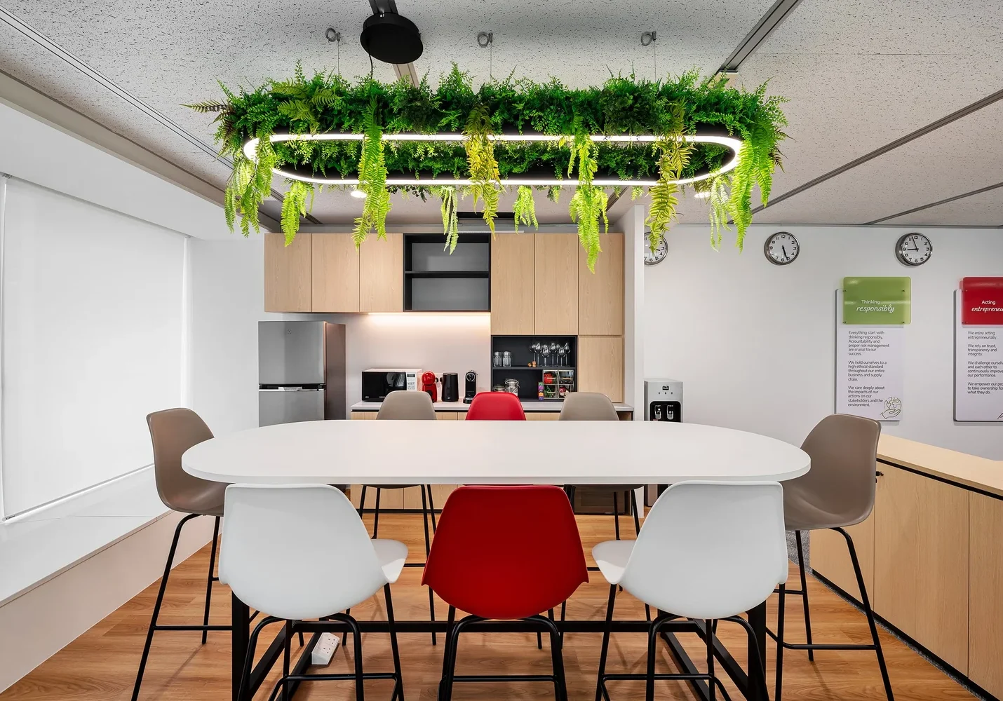 Biophilic office pantry with suspended greenery and communal seating