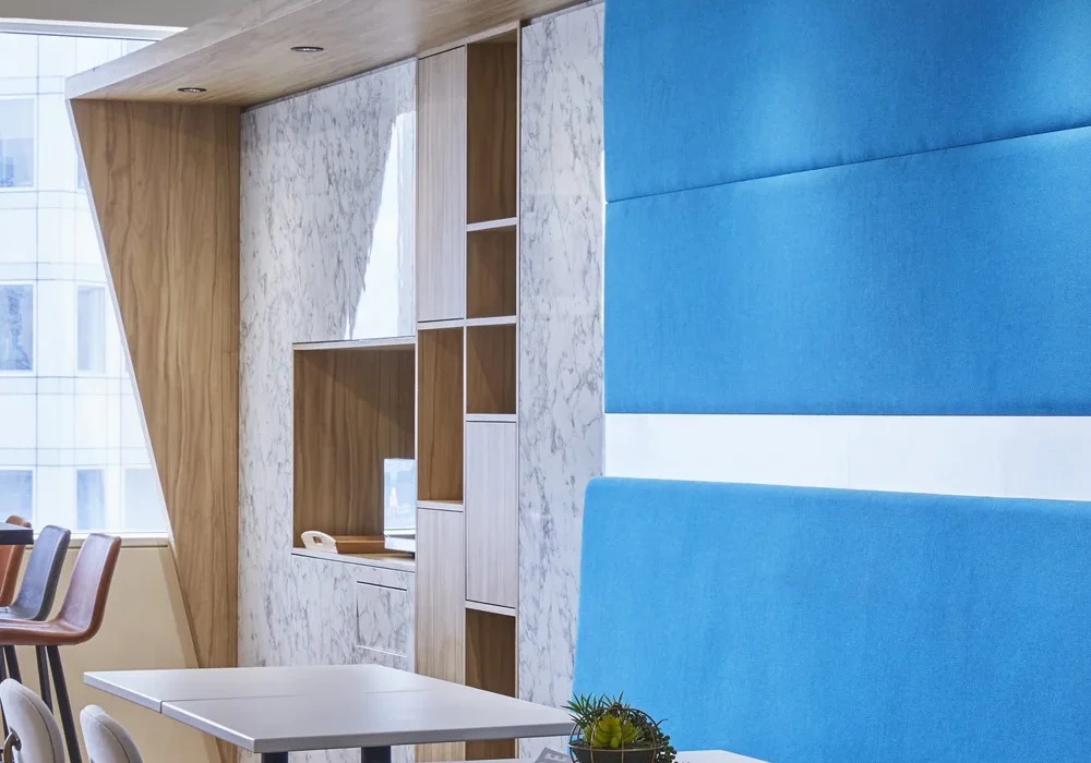 ASICS office breakout area with blue upholstered seating and timber finishes