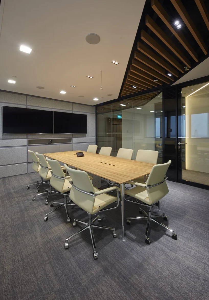 L.E.K. Consulting boardroom with timber meeting table and dual display screens